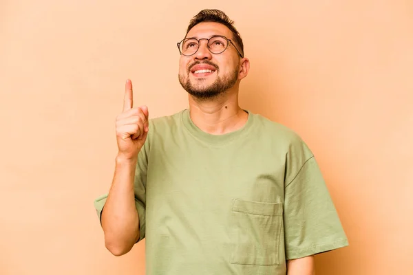Mladý Hispánec Izolovaný Béžovém Pozadí Ukazuje Oběma Předními Prsty Nahoru — Stock fotografie