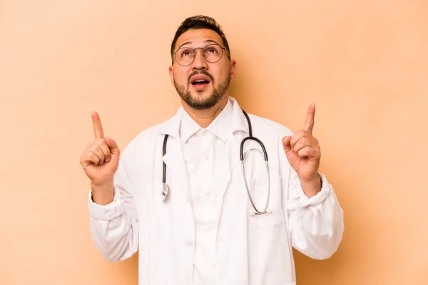 Hispanic Doctor Man Isolated Beige Background Pointing Upside Opened Mouth — Zdjęcie stockowe