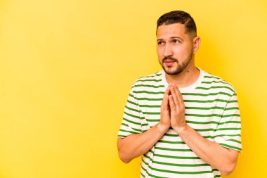 Latin kökenli genç bir adam sarı arka planda izole edilmiş. Aklında bir plan kuruyor..