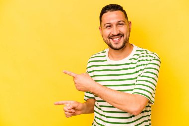 Sarı arka planda izole edilmiş genç bir İspanyol işaret parmağıyla işaret ederek heyecanlanıyor..