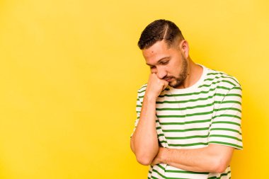 Sarı arka planda izole edilmiş, üzgün ve dalgın hisseden genç bir İspanyol fotokopi odasına bakıyor..