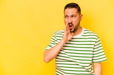 Sarı arka planda izole edilmiş genç İspanyol bir adam gizli bir sıcak fren haberi veriyor ve yana bakıyor.