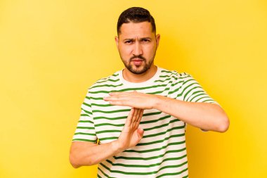 Sarı arka planda izole edilmiş genç İspanyol bir adam bir mola hareketi gösteriyor..