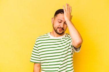 Sarı arka planda izole edilmiş genç bir İspanyol bir şeyi unutuyor. Alnına avuç içi ve gözlerini kapatıyor..