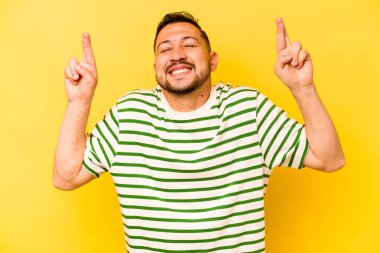 Genç İspanyol adam sarı arka planda izole edilmiş şans dilemek için şans diliyor.