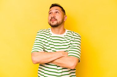 Genç İspanyol adam sarı arka planda izole edilmiş hedeflerine ve amaçlarına ulaşma hayali kuruyor.