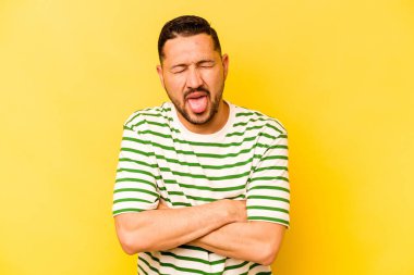 Sarı arka planda izole edilmiş genç bir İspanyol komik ve dost canlısı bir dil uzatıyor..