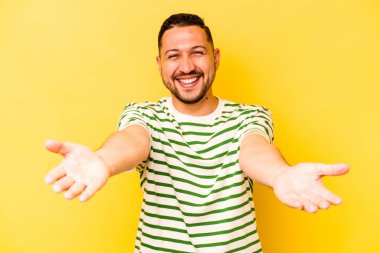 Sarı arka planda izole edilmiş genç bir İspanyol hoş geldin ifadesi sergiliyor..