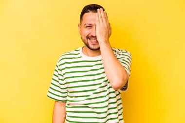 Sarı arka planda izole edilmiş genç bir İspanyol yüzünün yarısını palmiyeyle kaplayarak eğleniyor..