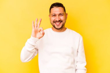 Genç İspanyol adam sarı arka planda izole edilmiş neşeli ve kendinden emin..