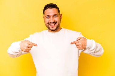 Sarı arka planda izole edilmiş genç bir İspanyol parmağını göstererek şaşırdı, geniş bir gülümsemeyle..