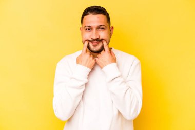 Latin kökenli genç adam sarı arka planda iki seçenek arasında kuşkulanıyor..