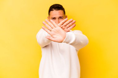 Sarı arka planda izole edilmiş genç İspanyol bir adam inkar hareketi yapıyor.