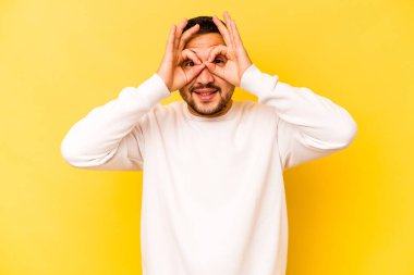 Sarı arka planda izole edilmiş genç İspanyol adam gözlerinde iyi işaretler gösteriyor.