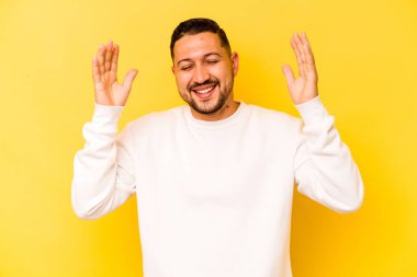 Genç İspanyol adam sarı arka planda izole edilmiş neşeli bir şekilde gülüyor. Mutluluk kavramı.