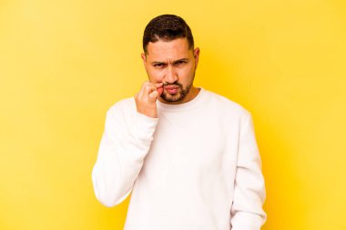 Sarı arka planda izole edilmiş genç İspanyol adam parmakları dudaklarında bir sır saklıyor..