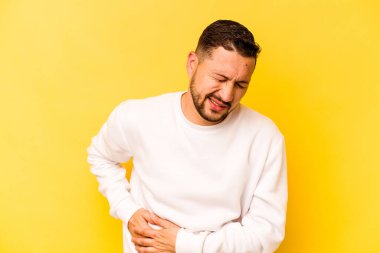 Sarı arka planda karaciğer ağrısı çeken, karnı ağrıyan genç bir İspanyol..