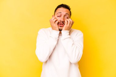 Genç İspanyol adam sarı arka planda izole edilmiş ağlıyor, bir şeyden memnun değil, acı ve kafa karışıklığı konsepti..