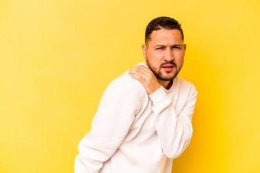 Sarı arka planda izole edilmiş, omuz ağrısı olan genç bir İspanyol..