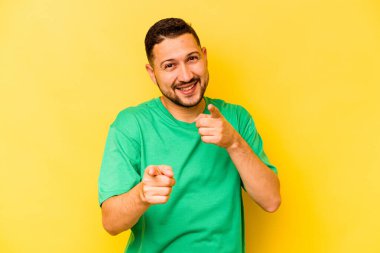 Sarı arka planda izole edilmiş genç bir İspanyol, parmaklarıyla ön tarafı işaret ediyor..