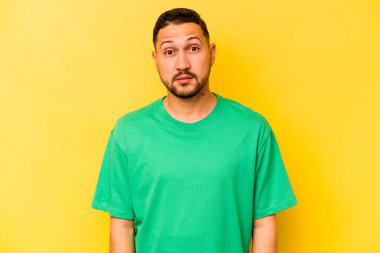 Genç İspanyol adam sarı arka planda izole edilmiş üzgün, ciddi yüzlü, mutsuz ve hoşnutsuz..