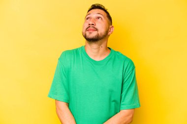 Sarı arka planda izole edilmiş genç bir İspanyol. Rahatlamış ve mutlu bir şekilde gülüyor. Boynunda dişler var..