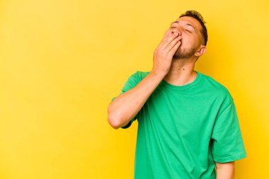 Genç İspanyol adam sarı arka planda izole edilmiş gülerek, kaygısız, doğal duygularla gülüyor..