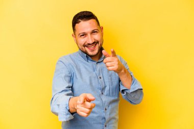 Sarı arka planda izole edilmiş genç bir İspanyol. Önü gösteren neşeli gülücükler..