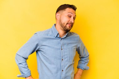 Genç İspanyol adam sarı arka planda izole edilmiş hedeflerine ve amaçlarına ulaşma hayali kuruyor.