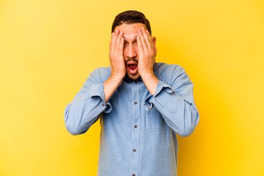 Sarı arka planda izole edilmiş genç bir İspanyol yüzünün yarısını palmiyeyle kaplayarak eğleniyor..