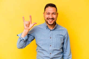 Sarı arka planda izole edilmiş genç İspanyol bir adam boynuzlarını devrim konsepti olarak gösteriyor..