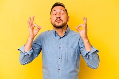 Sarı arka planda izole olmuş genç İspanyol adam sıkı çalışma gününden sonra rahatlıyor. Yoga yapıyor..