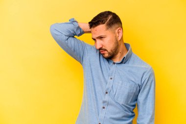 Sarı arka planda izole edilmiş genç bir İspanyol. Çok yorgun ve uykulu. Elini başının üstünde tutuyor..