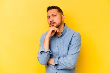 Sarı arka planda izole edilmiş genç bir İspanyol şüpheli, belirsiz, seni muayene ediyor..