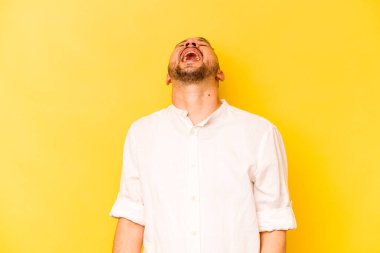 Sarı arka planda izole edilmiş genç bir İspanyol. Rahatlamış ve mutlu bir şekilde gülüyor. Boynunda dişler var..