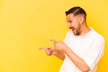 Latin kökenli genç adam sarı arka planda izole edilmiş, başparmak uzakta, gülüyor ve kaygısız..