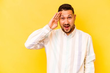 Sarı arka planda izole edilmiş genç İspanyol yüksek sesle bağırıyor, gözleri açık ve elleri gergin tutuyor..