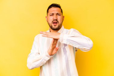 Sarı arka planda izole edilmiş genç İspanyol bir adam bir mola hareketi gösteriyor..