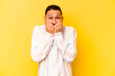 Sarı arka planda izole edilmiş, tırnak yiyen, gergin ve endişeli genç bir adam..