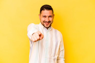 Sarı arka planda izole edilmiş genç bir İspanyol. Önü gösteren neşeli gülücükler..