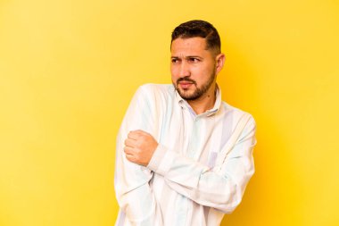 Sarı arka planda izole edilmiş genç İspanyol adam kafası karışmış, şüpheli ve güvensiz hissediyor..