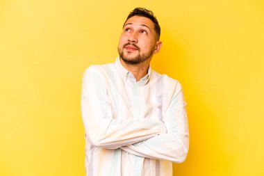 Genç İspanyol adam sarı arka planda izole edilmiş hedeflerine ve amaçlarına ulaşma hayali kuruyor.