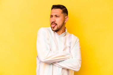 Sarı arka planda izole edilmiş genç bir İspanyol komik ve dost canlısı bir dil uzatıyor..