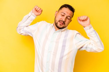 Sarı arka planda izole edilmiş genç bir İspanyol. Kollarını uzatıyor, rahat duruyor..