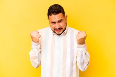 Sarı arka planda izole edilmiş genç İspanyol adam gergin elleriyle çığlık atıyor..