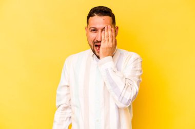 Sarı arka planda izole edilmiş genç bir İspanyol yüzünün yarısını palmiyeyle kaplayarak eğleniyor..