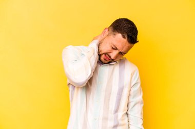 Genç İspanyol bir adam sarı arka planda izole edilmiş, sabit yaşam tarzından dolayı boyun ağrısı çekiyor..