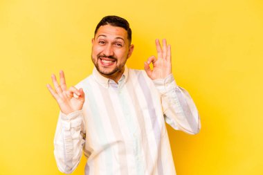 Genç İspanyol adam sarı arka planda izole edilmiş neşeli ve kendinden emin..