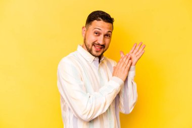 Genç İspanyol adam sarı arka planda izole edilmiş enerjik ve rahat hissediyor, ellerini ovuşturuyor kendinden emin..