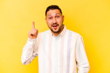 Sarı arka planda izole edilmiş genç İspanyol bir adamın bir fikri, ilham konsepti var..